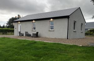 a white house with two benches in front of it at Tadgh's Cottage in Ennis