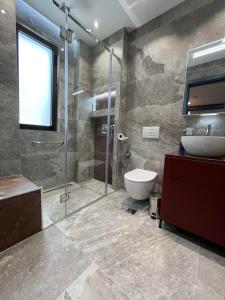 een badkamer met een douche, een toilet en een wastafel bij Fox Apartments in Tirana