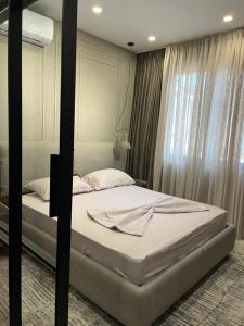 een slaapkamer met een bed met witte lakens en een raam bij Fox Apartments in Tirana
