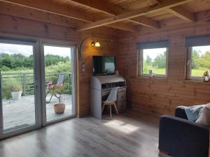 una sala de estar con TV en una cabaña de madera en Domek Gościnny, en Darłowo