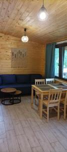a room with a table and chairs and a blue couch at Zielenina Leśny Domek in Mierzeszyn