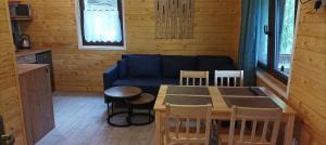 a living room with a couch and a table and chairs at Zielenina Leśny Domek in Mierzeszyn