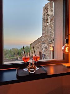 due bicchieri da vino seduti su un tavolo accanto a una finestra di The White Domus a Taormina