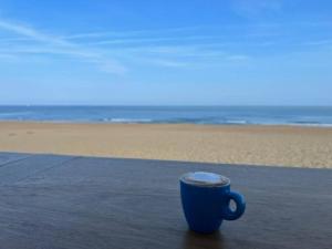 eine blaue Kaffeetasse auf einem Tisch am Strand in der Unterkunft Maison à Chiberta, à 5 minutes à pieds des plages in Anglet