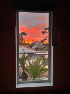 ein Fenster mit Blick auf ein Haus und Palmen in der Unterkunft Maison à Chiberta, à 5 minutes à pieds des plages in Anglet