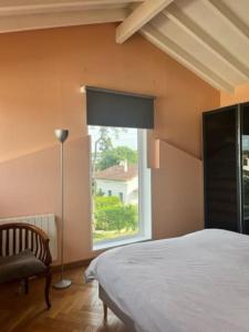 ein Schlafzimmer mit einem Bett, einem Fenster und einem Stuhl in der Unterkunft Maison à Chiberta, à 5 minutes à pieds des plages in Anglet