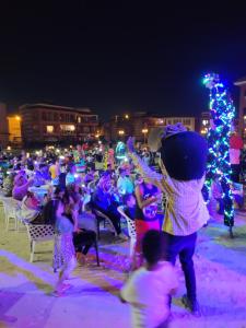 a large crowd of people dancing in front of a christmas tree at Porto Matrouh for FAMILIES ONLY in Marsa Matruh
