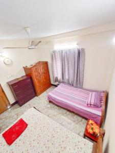 a bedroom with a bed and a dresser and a window at Modern 3 Bedroom Flat in Sylhet in Sylhet