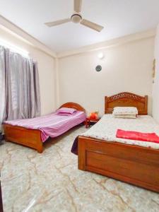 a bedroom with two beds and a ceiling fan at Modern 3 Bedroom Flat in Sylhet in Sylhet