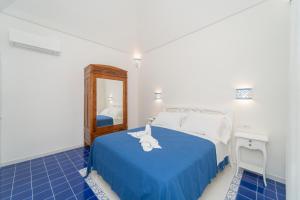 een slaapkamer met een bed met een blauwe deken en een spiegel bij Relais Capitolo in Maiori