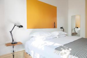 a bedroom with a white bed with a yellow wall at Cheese & Wine Lapa in Lisbon