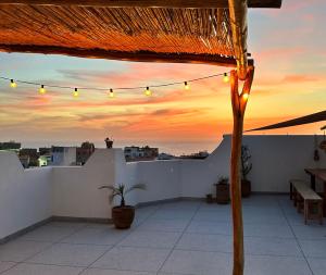 eine Dachterrasse mit Blick auf den Sonnenuntergang in der Unterkunft Wavy Days in Tamraght Ouzdar