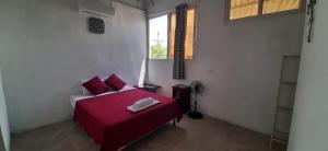 1 dormitorio con cama roja y ventana en Casa Zoila Hospedaje frente al lago Lakefront lodging, en Flores