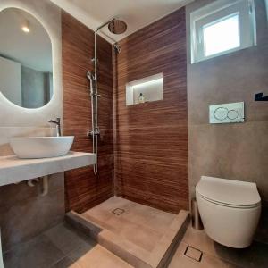 a bathroom with a toilet and a sink and a mirror at nisaki rooms & apartments in Methana