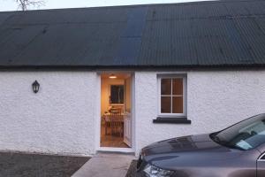 Casa blanca con techo negro y mesa en Ivy Cottage, en Wexford