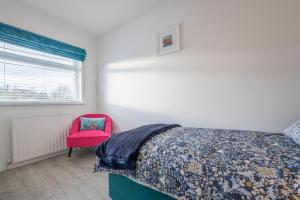 1 dormitorio con 1 cama y 1 silla rosa en Castle Lane House, en Enniskillen