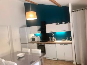 uma cozinha com armários brancos e uma parede azul em Gîte du centre- Maison avec extérieur en centre ville em Mèze