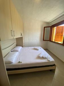 a bedroom with a bed with white sheets and a window at Villa Juniperus Porto Pino in SantʼAnna Arresi +25 photos