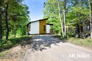 ein kleines gelbes und weißes Haus im Wald in der Unterkunft Arianna- Chalet avec spa & piscine in Pont-Rouge