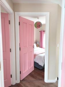 a pink door leading to a bedroom with a bed at Unboring Holiday Let, Ballina, Mayo in Ballina