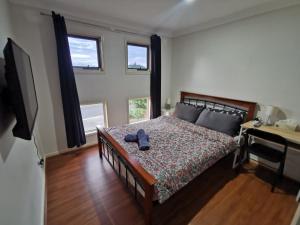 a bedroom with a bed and a desk and two windows at Shared house with other guests near shopping center and theme parks in Gold Coast