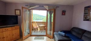 a living room with a couch and a television and a balcony at Aurora on the lake in Fužine
