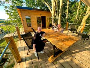 two people sitting at a wooden table on a deck at Zelený ostroff Treehouse in Jiříkov
