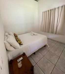 a small room with a bed with white sheets and pillows at Casa Trancoso in Trancoso