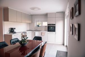 una cucina con mobili bianchi e un tavolo di legno di La Maison du cèdre a Dossenheim-sur-Zinsel