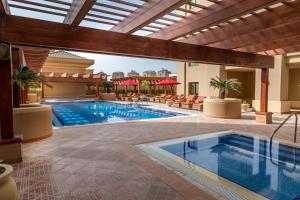 a pool in a hotel with chairs and a pool at Sedra Arjaan by Rotana in Doha