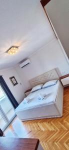 uma grande cama branca num quarto com piso em madeira em Rafael Apartment em Opuzen