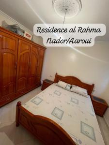 een slaapkamer met een bed met een houten bedframe bij Residence al Rahma 05 in Monte ʼArrouit