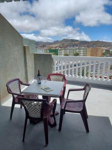 a table with two chairs and a bottle of wine on a balcony at APARTAMENTO C. LA VILLA TEO in Las Lagunas