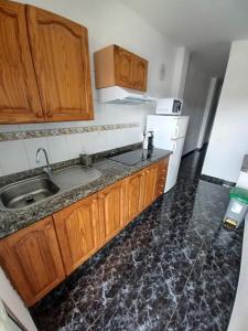 a kitchen with wooden cabinets and a sink at APARTAMENTO C. LA VILLA TEO in Las Lagunas