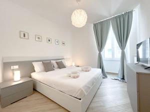 a white bedroom with a large bed and a television at [Lusso in Centro Storico] - WIFI - AC in Savona