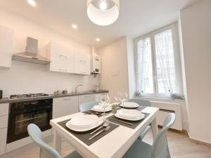 a white kitchen with a table with plates and glasses at [Lusso in Centro Storico] - WIFI - AC in Savona +17 photos