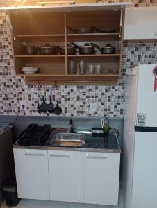 a kitchen with white cabinets and a sink and a refrigerator at Resiliência House in João Pessoa