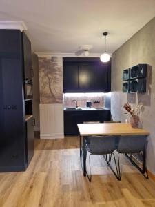a kitchen with black cabinets and a wooden table at Jacuzzi Apartamenty Gdańsk #2 - RELAX Apartments in Gdańsk