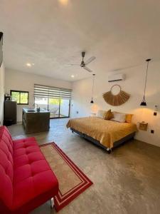 a bedroom with a large bed and a red couch at océano estudio 2 in Sayulita