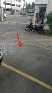 uma moto estacionada num parque de estacionamento com uma seta vermelha em Resiliência House em João Pessoa