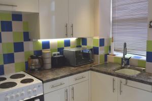 a kitchen with a sink and a stove and a microwave at Hill View Cottage in Bala