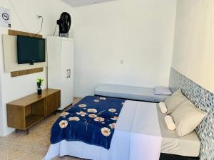 a small bedroom with a bed and a tv at Pousada Aconchego Ocian in Praia Grande