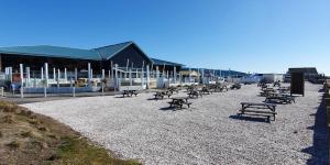 a row of benches sitting on a beach with a building at Althea, White Horse, Seal Bay Resort in Selsey