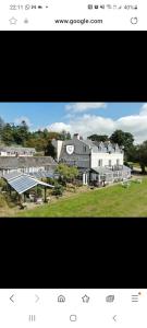 a picture of a large white building with a yard at Peacock Lodge - Sleeps 4 - 2 Bedrooms in East Looe