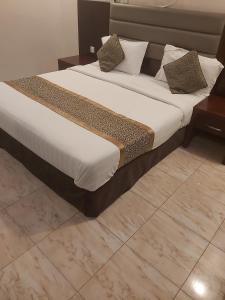 een bed met witte lakens en kussens in een kamer bij دانات الخليج in Al Khobar