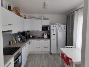 a kitchen with white cabinets and a white refrigerator at Omakotitalo rauhallisella alueella in Rauma