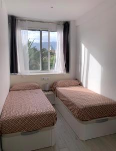 two beds in a room with a window at Entre el verde y el azul in Fuengirola
