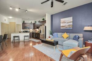 a living room with a blue couch and a kitchen at Lux Mid-Rise Walking Distance to NRG Stadium in Houston