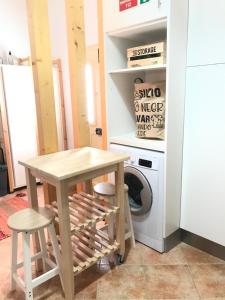 a table and two stools in a kitchen with a washing machine at Vila Velha Guest House in Mértola