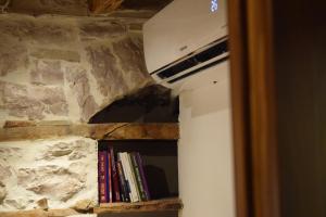 Un estante de libros con libros junto a una pared de piedra. en Braja House en Gjirokastër